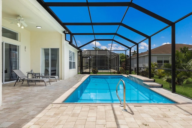 pool featuring a patio area, glass enclosure, and ceiling fan