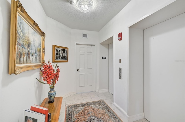 interior space featuring a textured ceiling, light tile patterned floors, and elevator