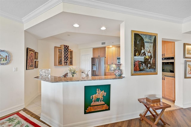 kitchen with ornamental molding, appliances with stainless steel finishes, and light hardwood / wood-style floors