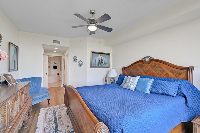 bedroom with ceiling fan, hardwood / wood-style floors, and connected bathroom