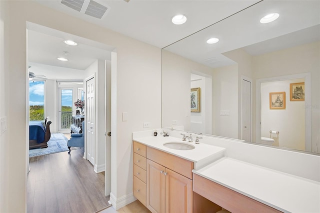 bathroom with vanity, toilet, hardwood / wood-style floors, and ceiling fan