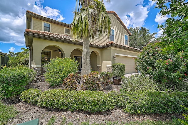 mediterranean / spanish home with stucco siding, a tiled roof, and an attached garage