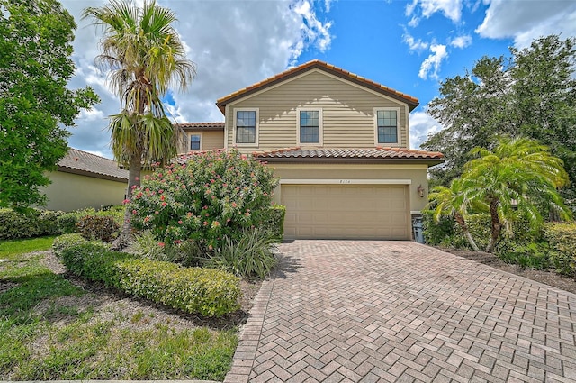 mediterranean / spanish-style home with stucco siding, a tile roof, decorative driveway, and a garage