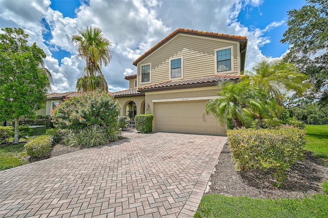 mediterranean / spanish-style home featuring decorative driveway, an attached garage, stucco siding, and a tile roof