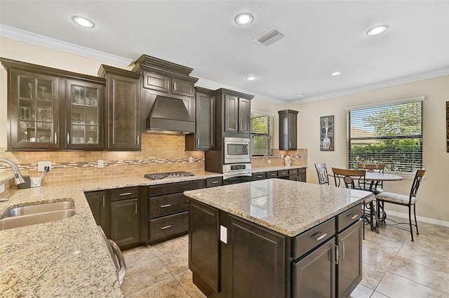 kitchen featuring range hood, visible vents, ornamental molding, stainless steel appliances, and a sink