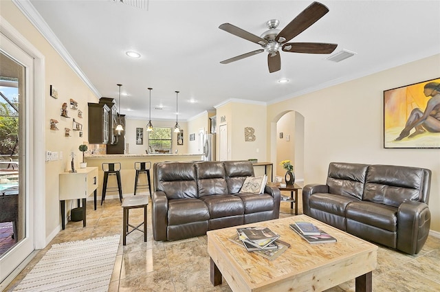 living area with visible vents, arched walkways, baseboards, and crown molding