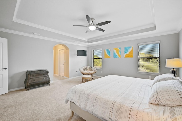 bedroom featuring arched walkways, multiple windows, and a raised ceiling