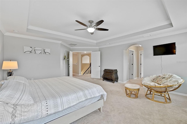 bedroom featuring baseboards, arched walkways, a raised ceiling, and light carpet