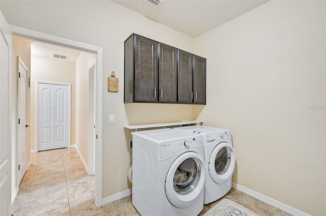 washroom with washer and dryer, baseboards, cabinet space, and visible vents