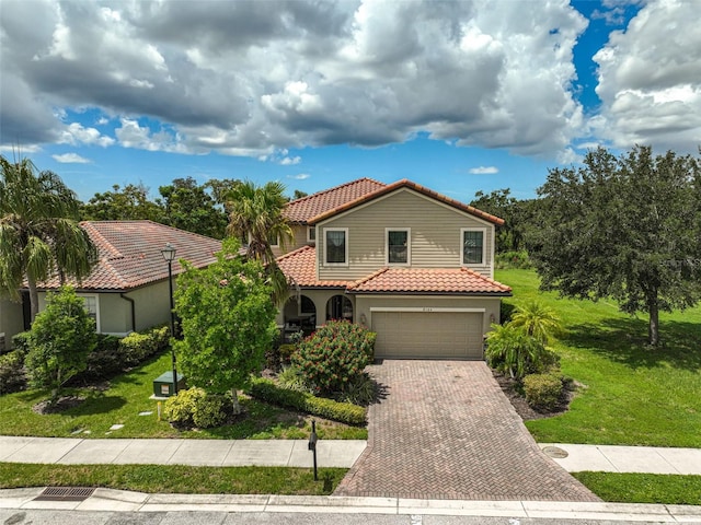 mediterranean / spanish-style home with stucco siding, decorative driveway, a front yard, a garage, and a tiled roof