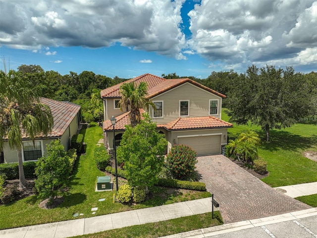 mediterranean / spanish-style home featuring stucco siding, driveway, a front lawn, a garage, and a tiled roof