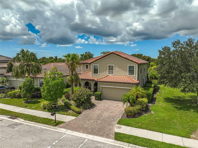 mediterranean / spanish house with a tile roof, a front yard, stucco siding, decorative driveway, and a garage