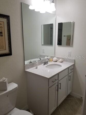 bathroom with tile patterned flooring, vanity, and toilet