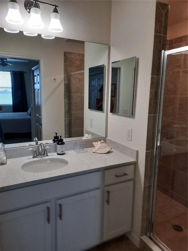 bathroom with ceiling fan, a shower with door, and vanity