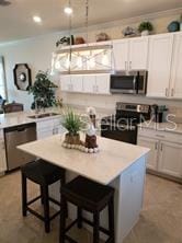 kitchen featuring stainless steel appliances, sink, white cabinets, a kitchen island, and a breakfast bar