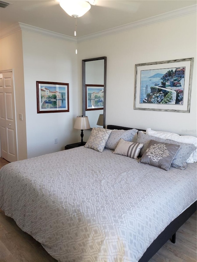 bedroom featuring hardwood / wood-style floors, ornamental molding, and a closet