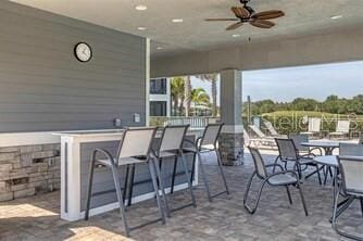 view of patio featuring ceiling fan and a bar