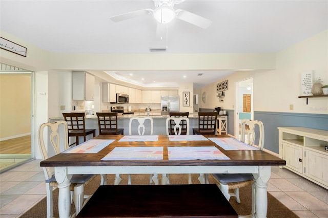 tiled dining space featuring ornamental molding, a tray ceiling, and ceiling fan