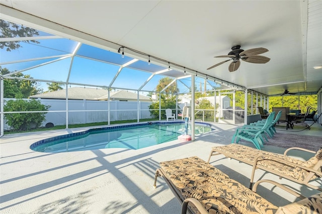 view of swimming pool with glass enclosure, ceiling fan, and a patio area