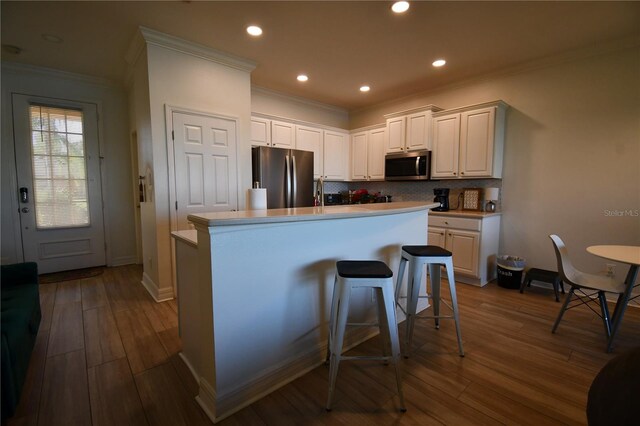 kitchen with dark wood-type flooring, stainless steel appliances, an island with sink, and white cabinetry