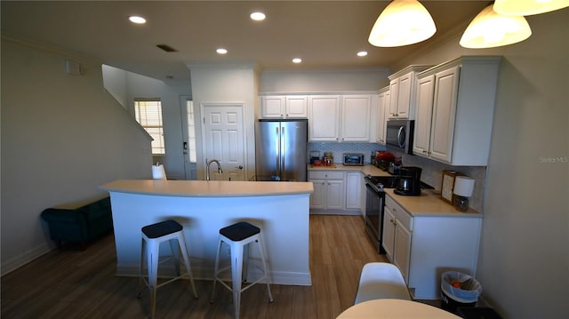 kitchen featuring a kitchen breakfast bar, dark hardwood / wood-style floors, appliances with stainless steel finishes, ornamental molding, and white cabinets