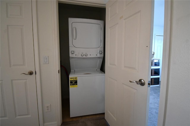 clothes washing area featuring dark colored carpet and stacked washing maching and dryer