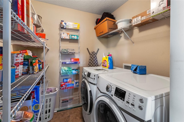 laundry room featuring washing machine and clothes dryer, a textured ceiling, and dark tile patterned floors