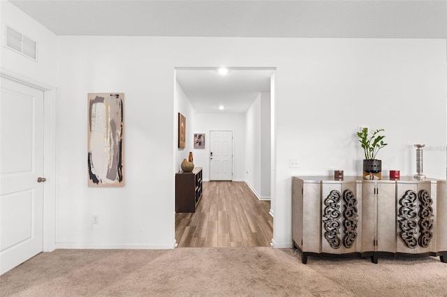 hall with carpet, visible vents, and baseboards