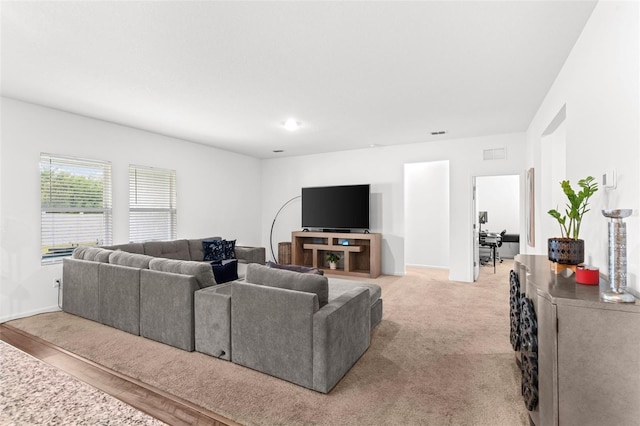 living room featuring baseboards, visible vents, and light colored carpet