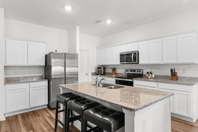 kitchen with white cabinetry, light wood-style flooring, appliances with stainless steel finishes, and a sink