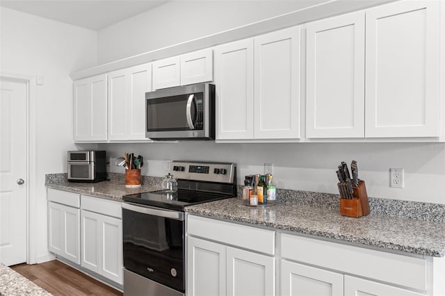 kitchen with light stone countertops, dark wood-style floors, white cabinetry, and stainless steel appliances