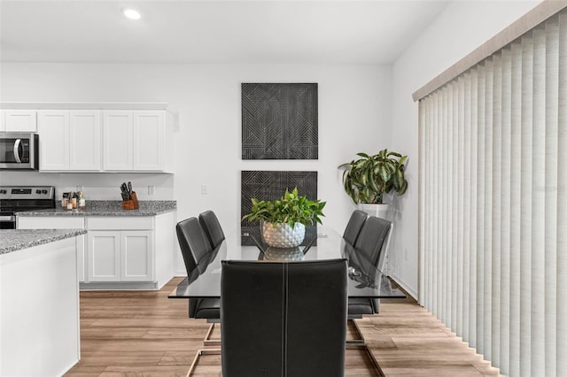 dining area with light wood finished floors, baseboards, and recessed lighting