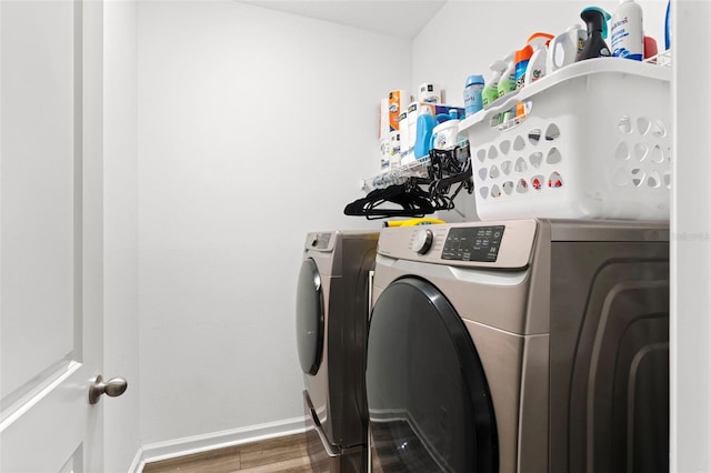 laundry area featuring washing machine and dryer, laundry area, baseboards, and wood finished floors