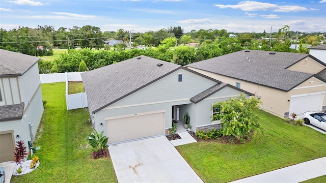 view of front of house featuring a garage, concrete driveway, roof with shingles, fence, and a front yard