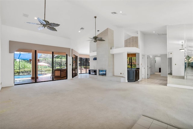 unfurnished living room with light carpet, high vaulted ceiling, and ceiling fan