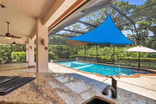 view of swimming pool with ceiling fan, a patio area, and a lanai