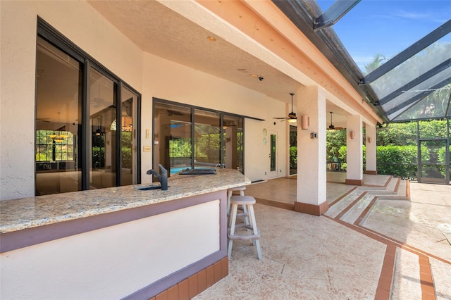 view of patio / terrace with ceiling fan, glass enclosure, and sink