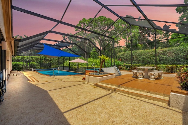 pool at dusk with a patio and a lanai