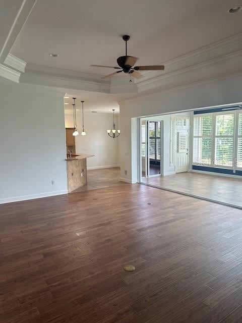 unfurnished living room with ceiling fan with notable chandelier, a raised ceiling, crown molding, and dark hardwood / wood-style floors