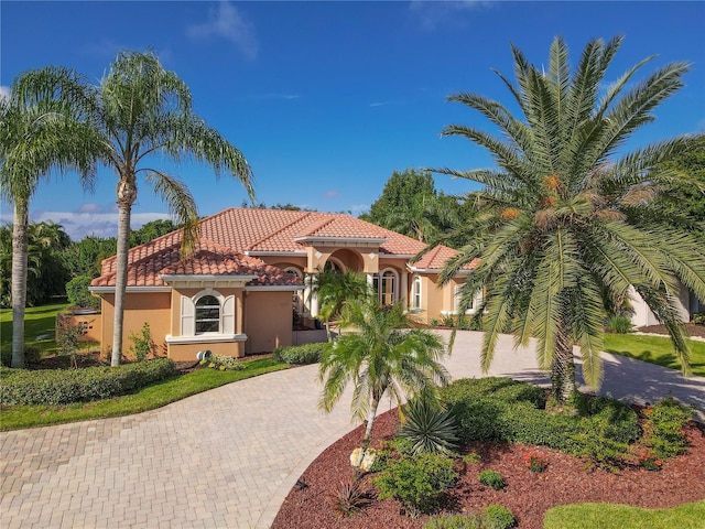 mediterranean / spanish house with stucco siding, decorative driveway, and a tiled roof