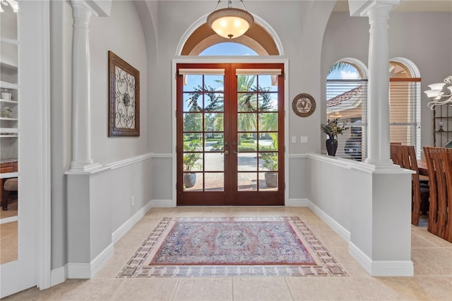 tiled foyer entrance with ornate columns, baseboards, and french doors