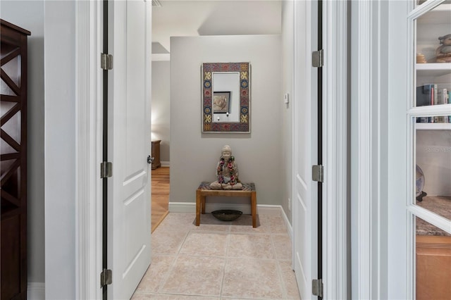 hall featuring baseboards and light tile patterned floors