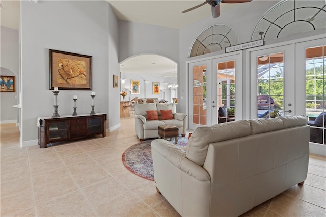 living area with light tile patterned flooring, baseboards, arched walkways, and french doors