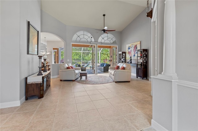 living area featuring light tile patterned floors, baseboards, a ceiling fan, ornate columns, and high vaulted ceiling