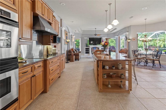 kitchen featuring light tile patterned floors, double oven, a fireplace, and under cabinet range hood