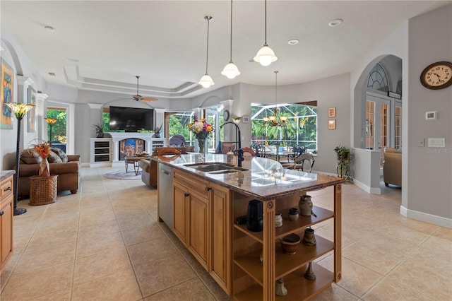 kitchen featuring light tile patterned floors, a fireplace, a tray ceiling, and a sink