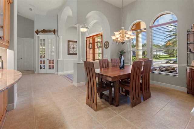 dining room with a chandelier, french doors, high vaulted ceiling, and ornate columns