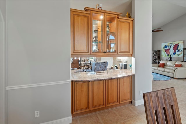 bar with light tile patterned floors, ceiling fan, and baseboards