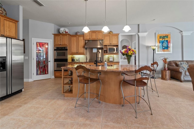 kitchen featuring light tile patterned flooring, under cabinet range hood, a sink, visible vents, and appliances with stainless steel finishes