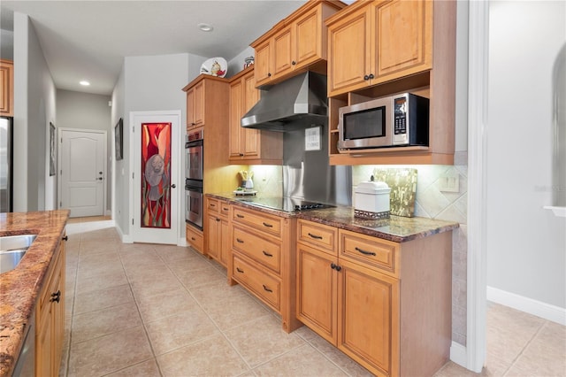 kitchen featuring light tile patterned flooring, under cabinet range hood, stainless steel appliances, dark stone counters, and tasteful backsplash